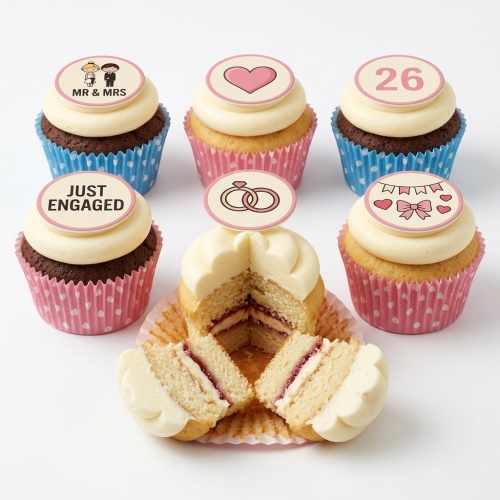 Six cupcakes with white frosting and engagement-themed toppers, including 'MR & MRS', 'JUST ENGAGED', heart, rings, banner, and a custom age '26'. Some chocolate, some vanilla sponge.