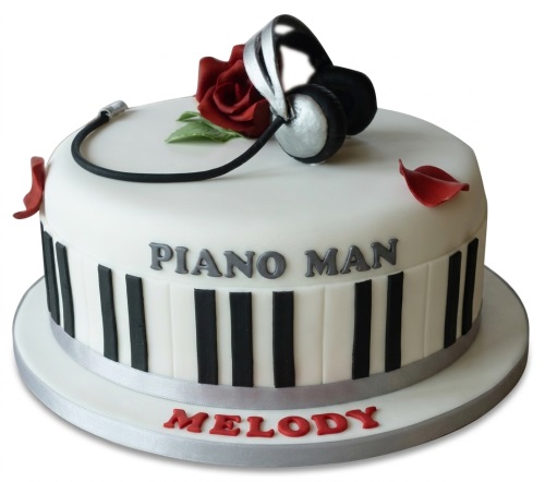 White round music theme birthday cake with silver headphones, red rose, and piano keys design.