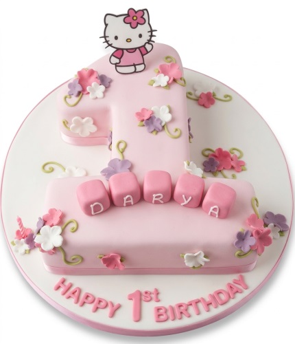 Pink Hello Kitty 1st birthday cake with white and purple floral decorations and custom name blocks.