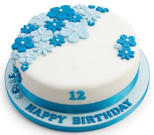 Round white birthday cake with blue sugar flowers, pearl details, blue ribbon, and custom age number.
