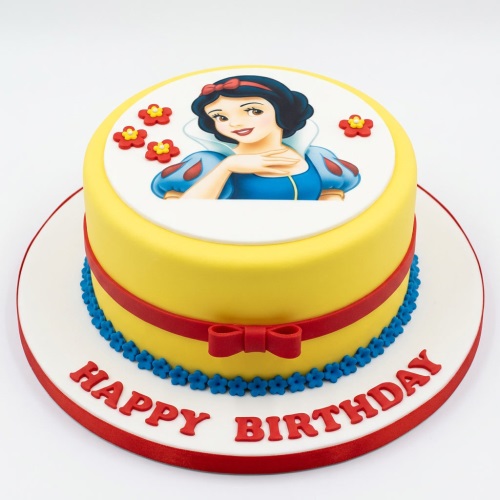 Round yellow Snow White birthday cake with red ribbon, blue flowers, and 'Happy Birthday' text.