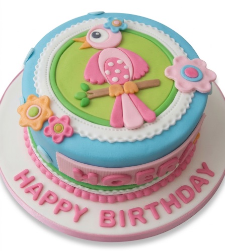 Round light blue and pink birthday cake with a fondant bird and colourful flowers, personalised for a girl's birthday.