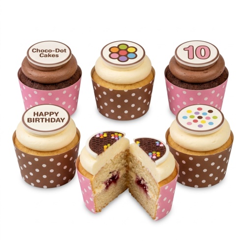 Assortment of colourful birthday cupcakes with custom age and Happy Birthday toppers, in pink and brown polka dot wrappers.