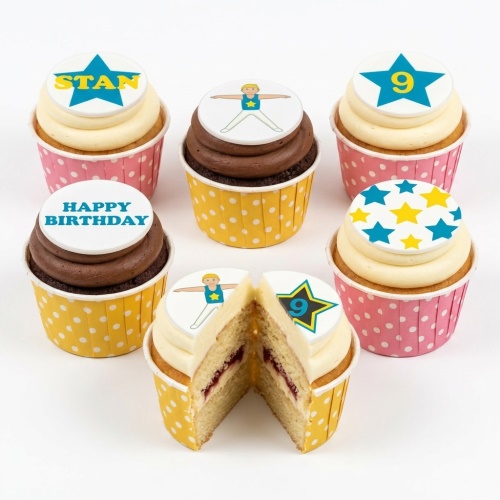 A selection of cupcakes with gymnastics figure, blue and yellow stars, and 'Happy Birthday' toppers.