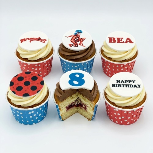 Miraculous Ladybug themed birthday cupcakes with custom age and name toppers, red and blue polka dot wrappers.