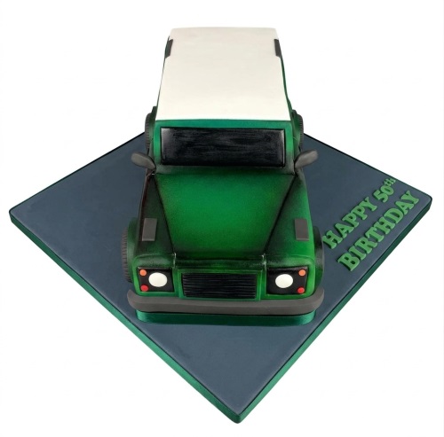 Green 3D Land Rover shaped birthday cake on a grey board with a custom message.