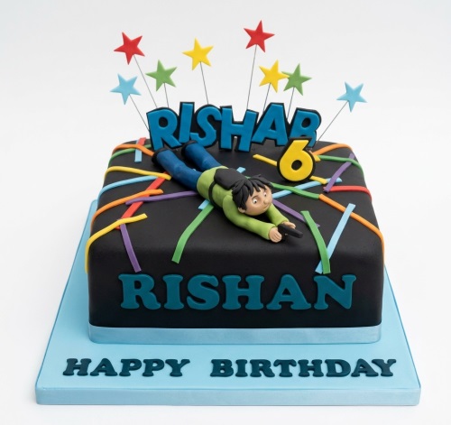 Black square cake with crawling character, multi-coloured laser lines, star toppers, and custom age.