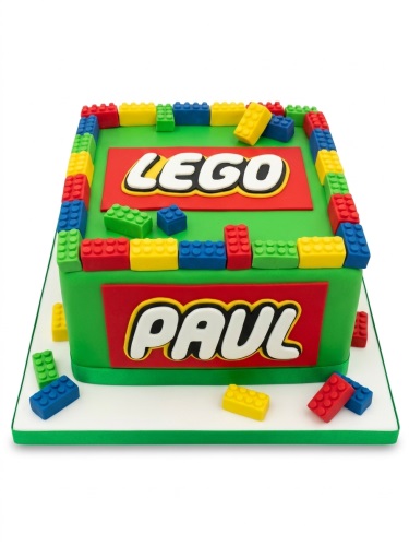Square green birthday cake decorated with red, yellow, blue, and green Lego-style bricks, with 'LEGO' on top and a custom name on the side.