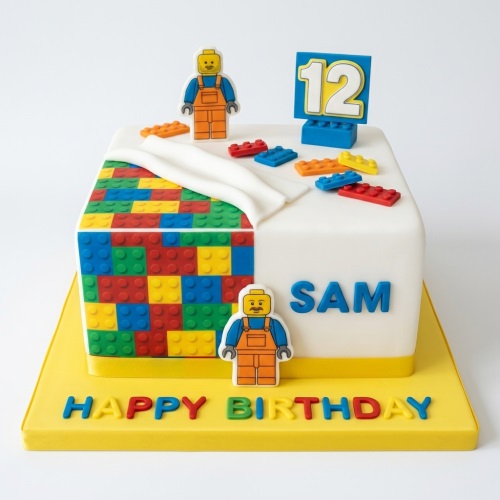 Square white birthday cake with colourful building blocks, two block figures, and a custom age topper.