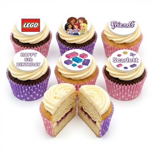 Selection of cupcakes with white frosting, featuring LEGO logo, LEGO Friends characters, and building block edible toppers in pink and purple cases.
