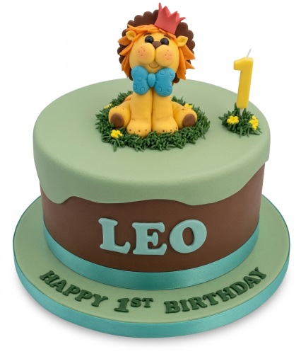 Round 1st birthday cake with a fondant lion topper, number 1 candle, and green and brown frosting.