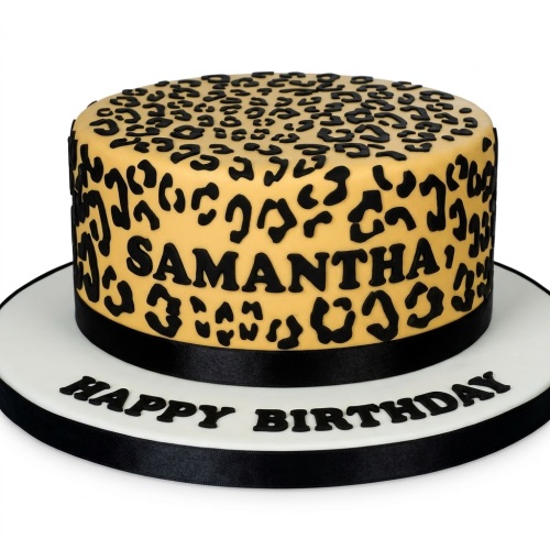 Round single-tier cake with yellow and black leopard print design, black ribbon, and a custom message on the board.