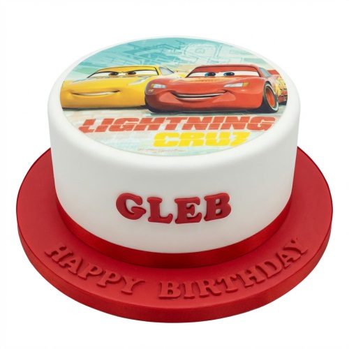 White round cake with an edible image of Disney Cars Lightning McQueen and Cruz Ramirez, a red ribbon, and a personalised name.