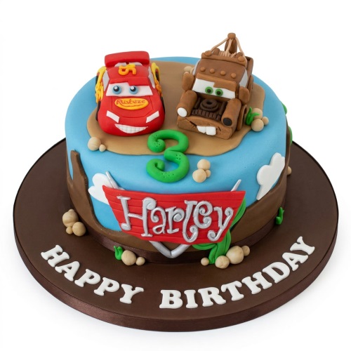 Round blue and brown Disney Cars birthday cake with Lightning McQueen and Mater figures, green custom age topper, and 'Happy Birthday' message.