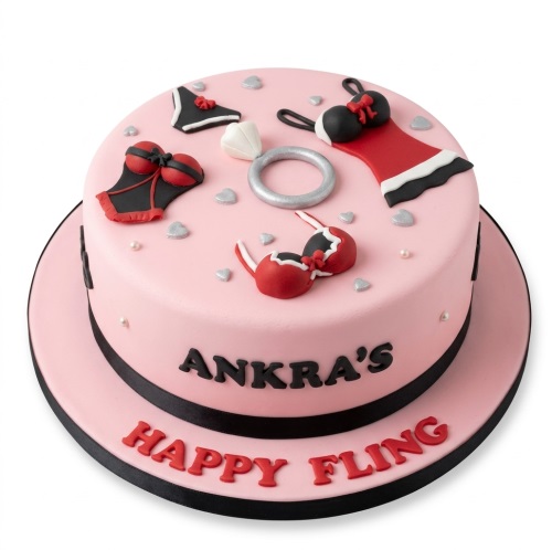 Pink round cake with red and black lingerie, silver hearts, and a diamond ring.