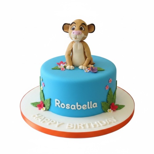 Round blue Simba Lion King birthday cake with 3D character topper, jungle leaves, and flowers.