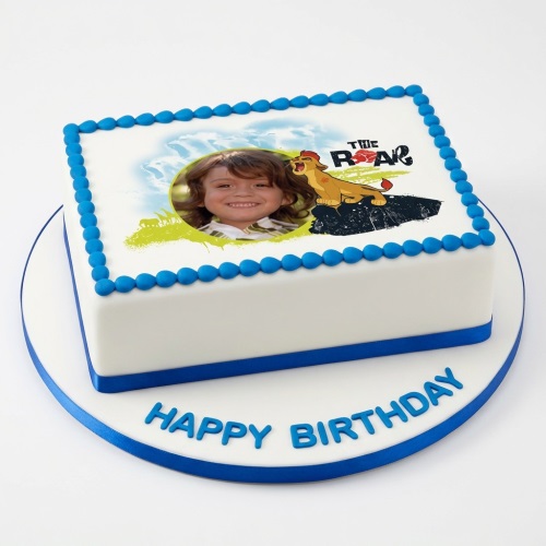 White rectangular cake with blue border and ribbon, featuring an edible image of a child's face and Kion from The Lion Guard, with 'Happy Birthday' on the board.