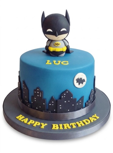 Blue Batman birthday cake with a fondant figure, cityscape, and moon.