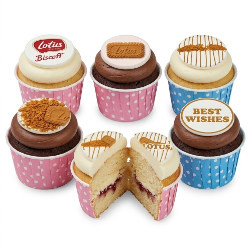 Six Lotus Biscoff cupcakes in pink and blue polka dot cases, with Biscoff biscuits, crumbs, and "Best Wishes" toppers. One cupcake is cut in half showing jam filling.
