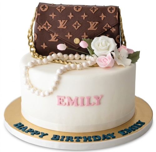 White single-tier cake with a brown designer handbag, pearls, and pink and white flowers.