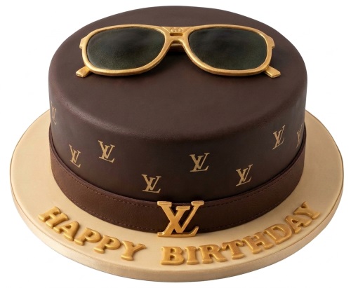 Round brown cake with gold LV logos, brown band, gold LV emblem, and gold sunglasses on top.