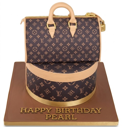 Two-tier LV branded handbag birthday cake with a brown monogram pattern and gold accents, on a brown board with a personalised message.