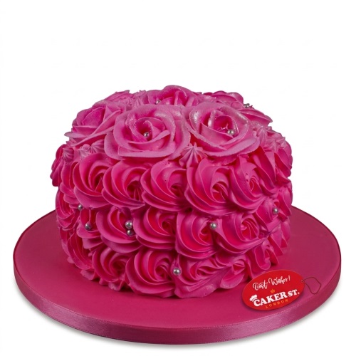 Round pink floral birthday cake with buttercream rose swirls and silver edible pearls.