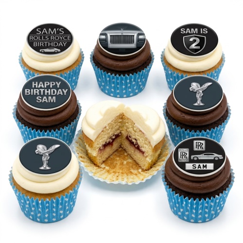 A collection of Rolls Royce themed birthday cupcakes with car images and logos, some with vanilla and some with chocolate frosting, in blue polka dot cases. One cupcake is cut open revealing vanilla sponge and jam filling.
