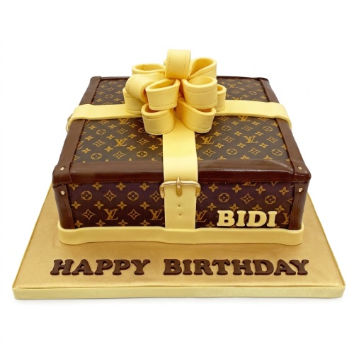 LV branded suitcase birthday cake with yellow ribbon and custom name on a gold board.