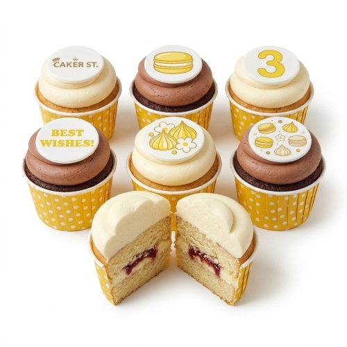 Assorted birthday cupcakes with yellow polka dot wrappers, white and chocolate icing, and sweet treat toppers including macarons and meringues, with a custom age topper and a 'Best Wishes' message.