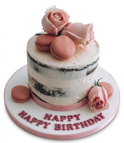 Round naked birthday cake with pink roses, macarons, and "Happy Birthday" message.