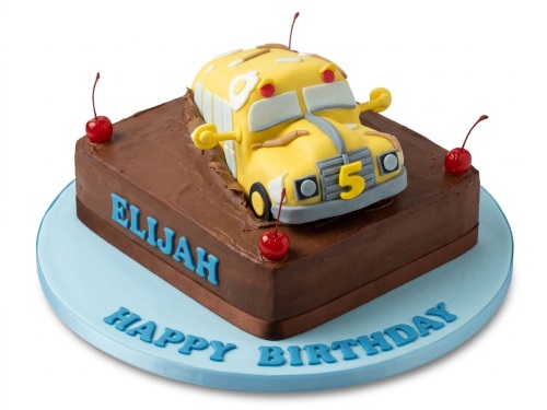 Yellow bus themed birthday cake in brown 'mud' with red cherries, featuring a custom age topper and personalised name.