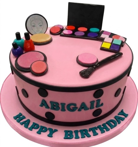 Round pink birthday cake decorated with edible makeup palettes, nail polish, and a brush, with black polka dots and a custom message.