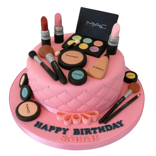 Two-tier pink makeup theme birthday cake with edible MAC cosmetics and 'Happy Birthday' message.