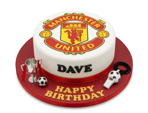 Round white Manchester United football birthday cake with club crest, trophy, football, and whistle.