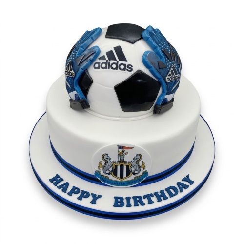 Two-tier white football birthday cake with edible Adidas ball, blue goalkeeper gloves, and Newcastle United crest.