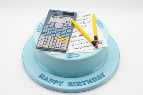 Light blue round birthday cake with edible calculator, mathematical equations, and yellow pencils.