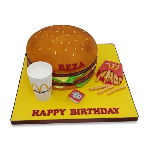3D McDonalds burger birthday cake with fries, drink, and ketchup on a yellow board.