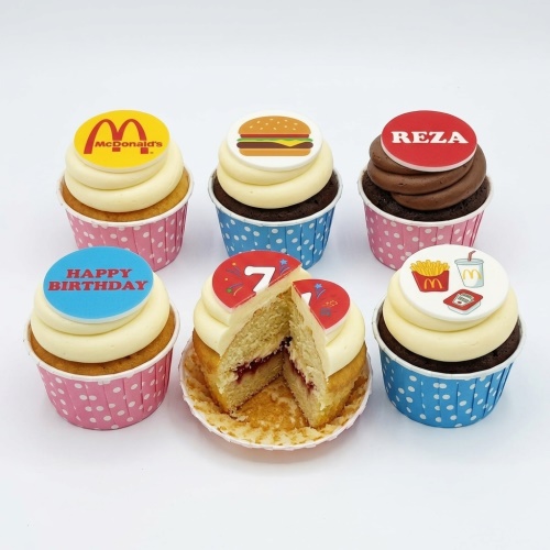 A set of fast food themed birthday cupcakes with edible toppers, including a burger, fries, fast food logo, and examples of custom age and name.