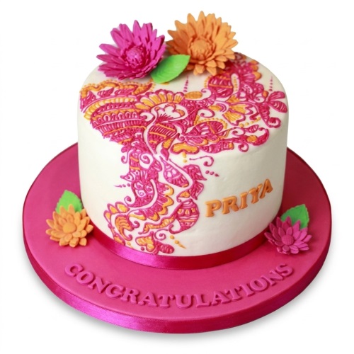 White round cake with vibrant henna-style floral design, sugar flowers, and a custom message.