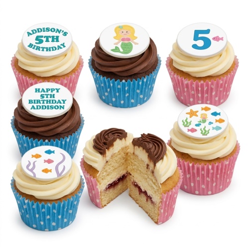 Mermaid and fish themed cupcakes with white and chocolate frosting, pink and blue wrappers, and custom age toppers.