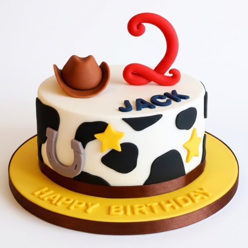 Round cowboy themed birthday cake with cow print, hat, horseshoe, stars, and custom age topper.