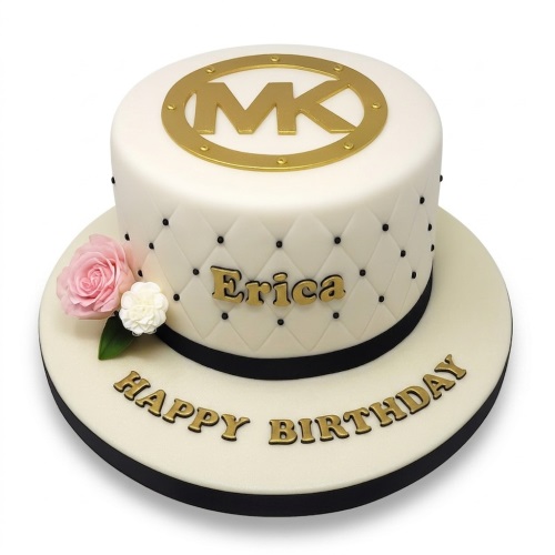 White Michael Kors designer birthday cake with gold MK logo, quilted pattern, and pink sugar flowers.