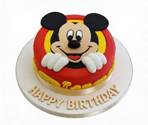 Round red and yellow Mickey Mouse themed birthday cake with Mickey's face and hands, on a white board with 'Happy Birthday' text.