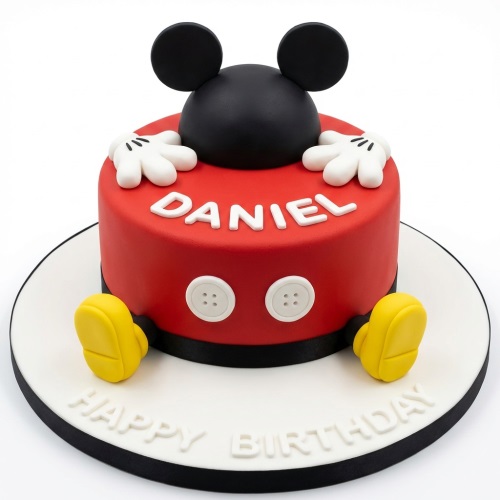 Mickey Mouse themed birthday cake with red, black, white, and yellow details, featuring a custom name and 'Happy Birthday' message.