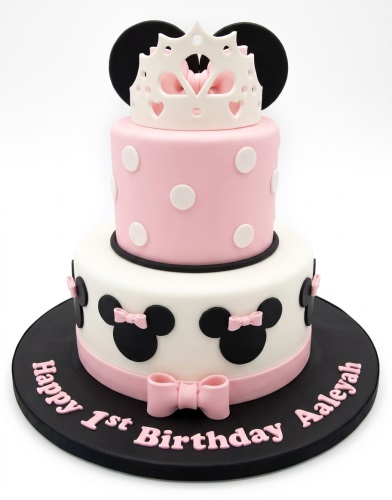 Two-tier Minnie Mouse Princess birthday cake with pink and white fondant, black Minnie ears, pink bows, and a white crown, with space for a custom message.