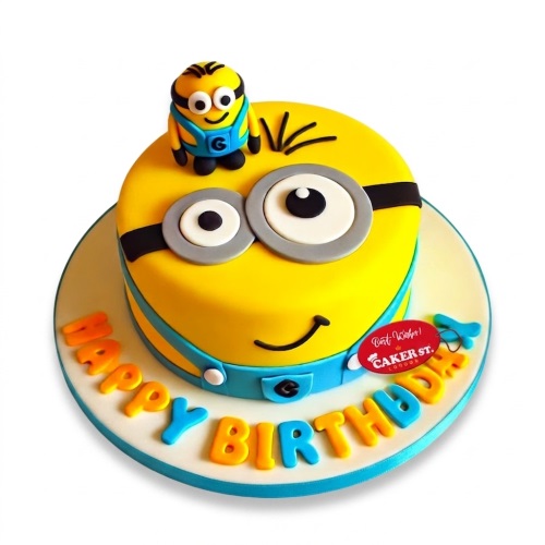 Round yellow Minion themed birthday cake with a Minion topper and 'Happy Birthday' message.