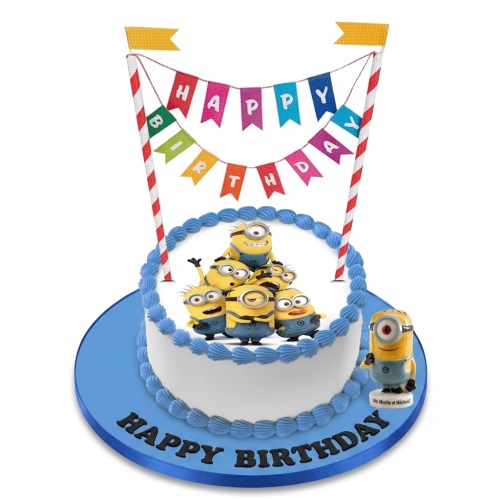 Round white Minions birthday cake with blue icing, 'Happy Birthday' bunting, and a 3D Minion figurine.