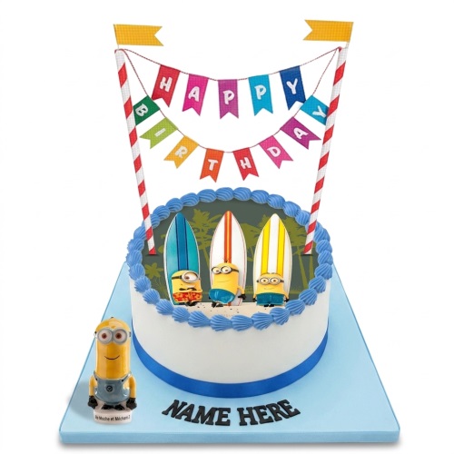 Round white Minions birthday cake with surfing theme, blue icing, and 'Happy Birthday' banner.