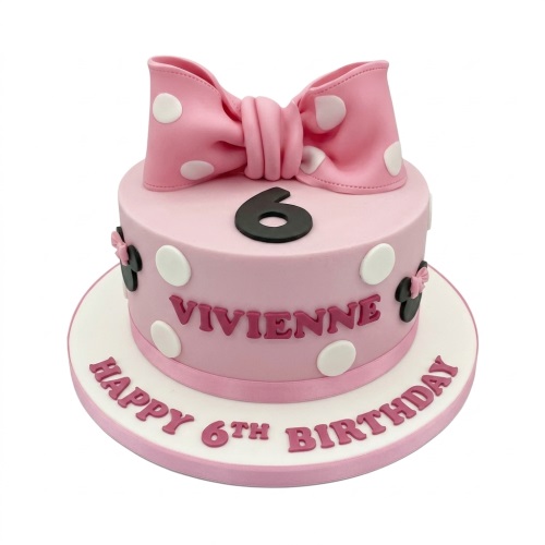 Pink Minnie Mouse themed birthday cake with a large bow, white polka dots, and custom age topper.